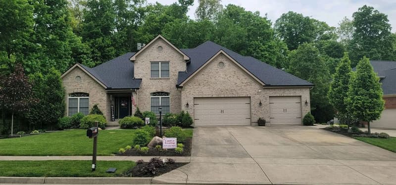 Brick house with dark shingle roof and yard sign